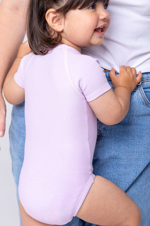 Flexisuit lavender bodysuit displayed on a model, showcasing its fitted design and soft fabric.